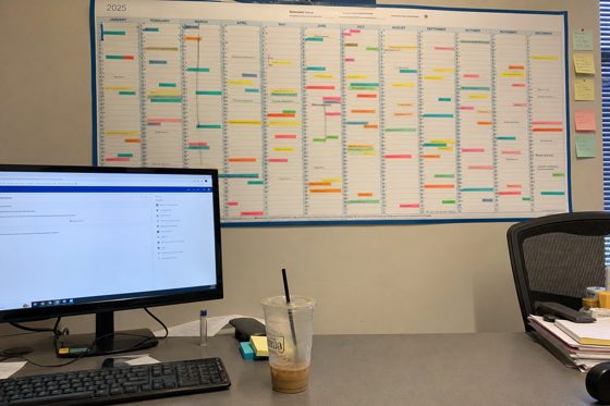 The reference photo: an office desk with a large wall planner covered in colour-coded washi tape.