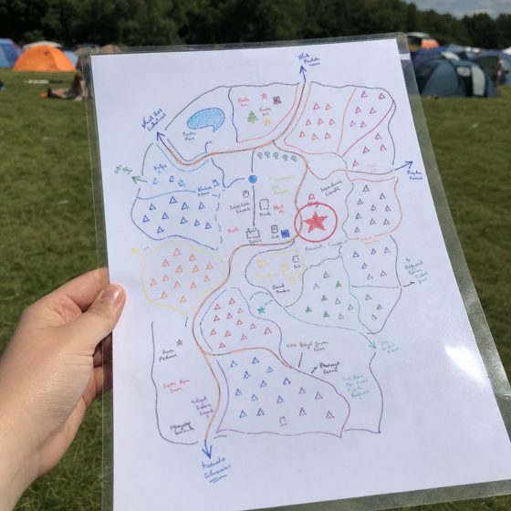 The reference photo: a hand-drawn, colour-coded campsite map, laminated, held up at a festival.